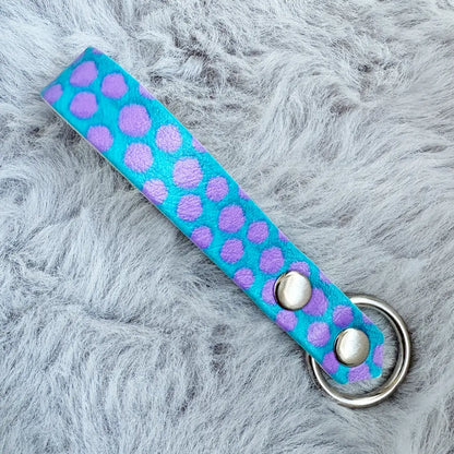 A key loop with Monster's Inc Sully blue and purple fur pattern, finished with a metal silver loop and two double cap rivets